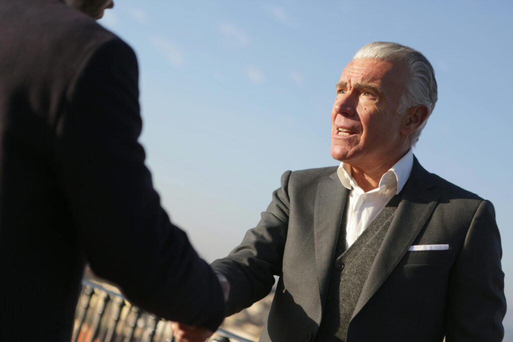 pexels-photo-3783585-3783585 Elderly businessman shakes hands outdoors, symbolizing trust and cooperation.